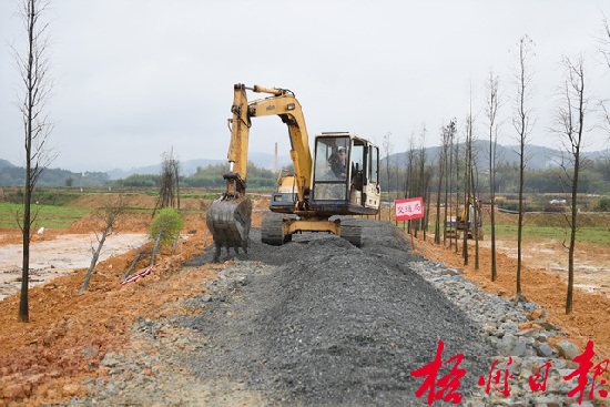 月12日，在萬(wàn)秀區(qū)夏郢鎮(zhèn)，施工機(jī)械正鋪設(shè)道路沙石。     夏郢鎮(zhèn)依托思良江兩岸山水自然風(fēng)光，開(kāi)發(fā)休閑農(nóng)業(yè)觀(guān)光項(xiàng)目。萬(wàn)秀區(qū)政府與市直有關(guān)部門(mén)共同在該項(xiàng)目的油菜花基地修建一條沙石道路，既方便游客，又為村民生產(chǎn)勞動(dòng)提供便利。      孟亞西  攝   